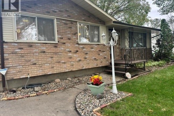 Close-up of the front entrance of a brick house with a decorative lamp post. - 147 Woodward Avenue, Regina