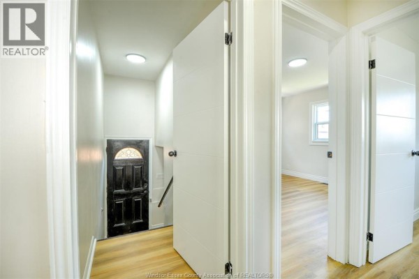 Interior hallway view showing closed doors, stairs to basement, and entrance door. - 1473 Labadie, Windsor