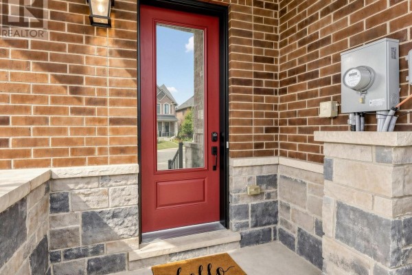 Red front door with glass pane and stone accents on brick townhouse exterior. - 1475 Blackmore Street, Innisfil