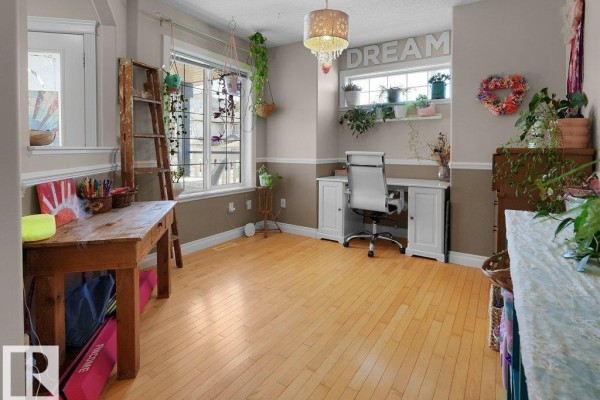 Interior room with light wood floors, storage shelves filled with toys, and an archway leading to a living room. - 1476 Mcmillian Wy Sw, Edmonton