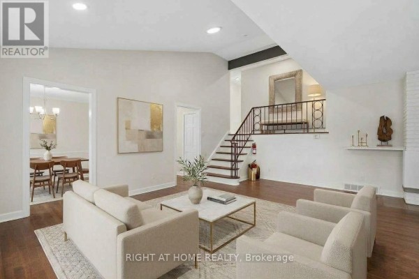 Living room with beige sofa, chairs, marble coffee table, fireplace, and staircase. - 1478 Orchard Ave Orchard Avenue, Ottawa