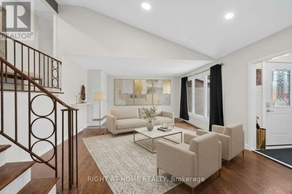 Living room with hardwood floors, white brick fireplace, and view of the staircase. - 1478 Orchard Ave Orchard Avenue, Ottawa