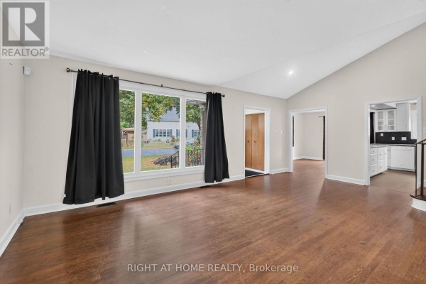 Living room with hardwood floors, white brick fireplace, and large windows with black curtains. - 1478 Orchard Ave Orchard Avenue, Ottawa