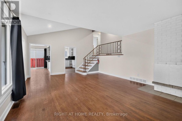 Living room with vaulted ceiling, hardwood floors, large windows, and view to kitchen. - 1478 Orchard Ave Orchard Avenue, Ottawa