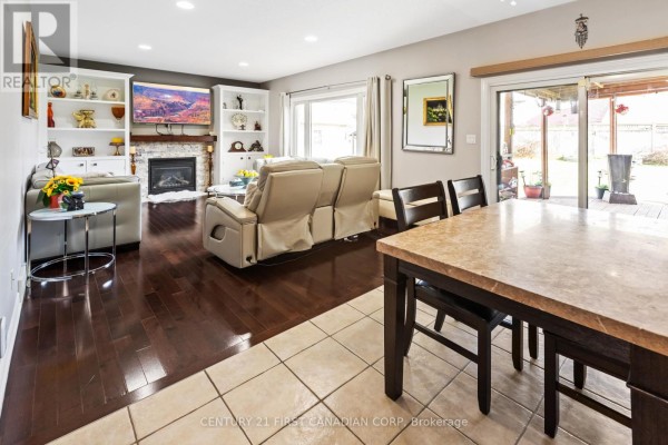 A living room with a fireplace and built-in bookshelves, adjacent to a dining area with a table and chairs. - 1479 Sandpiper Drive E, London North