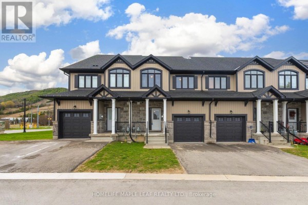 Front exterior of a beige and black townhouse complex with garages under a cloudy sky. - 104 Delphi Court, Blue Mountains