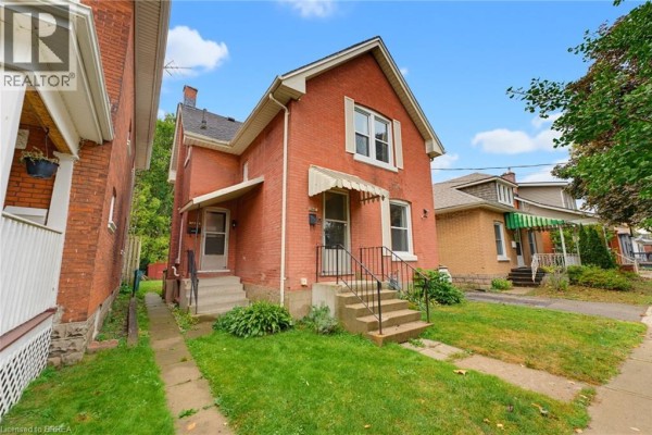 Front exterior of a red brick house with a lawn and sidewalk. - 148 Albion Street, Brantford