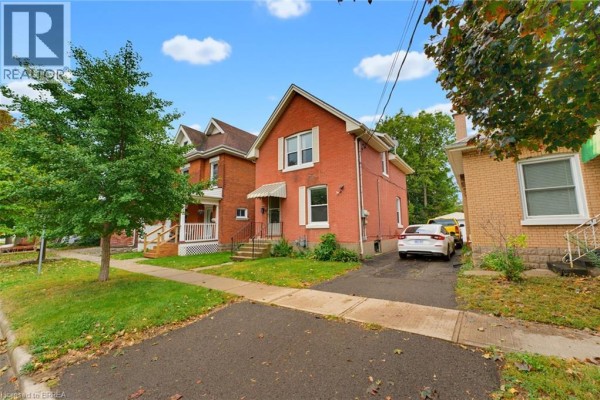 Side view of a red brick house with a driveway and parked car. - 148 Albion Street, Brantford