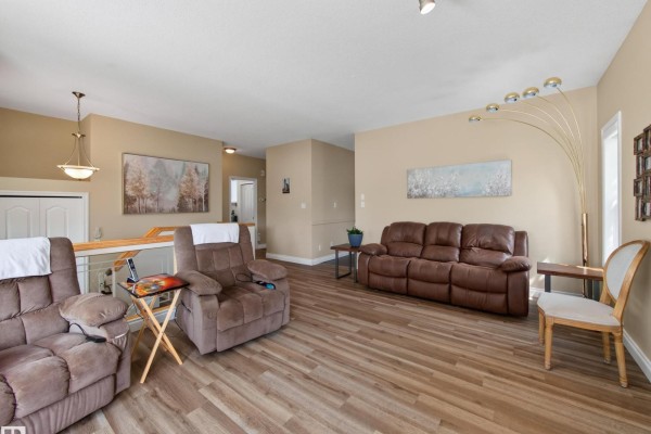 Living room with two brown recliners, a brown sofa, light wood floors, and beige walls. - 148 Forrest Dr, Sherwood Park