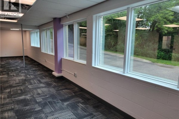 Interior office space with large windows, beige walls, and patterned carpet. - 148 Manitou Drive Unit# B101, Kitchener