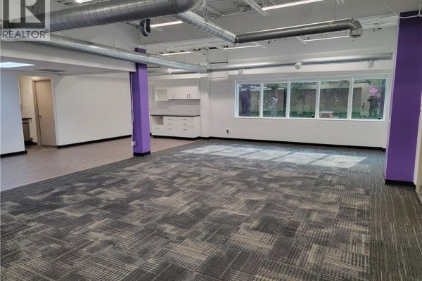 Large open commercial space with patterned carpet, white cabinets, and windows. - 148 Manitou Drive Unit# B101, Kitchener
