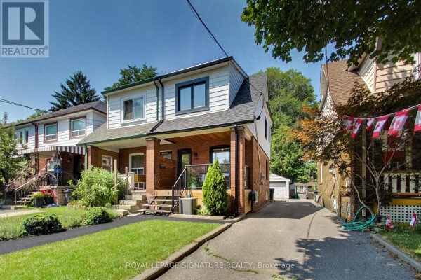 Front exterior of a red brick semi-detached house with a driveway. - 148 Mortimer Avenue, Toronto