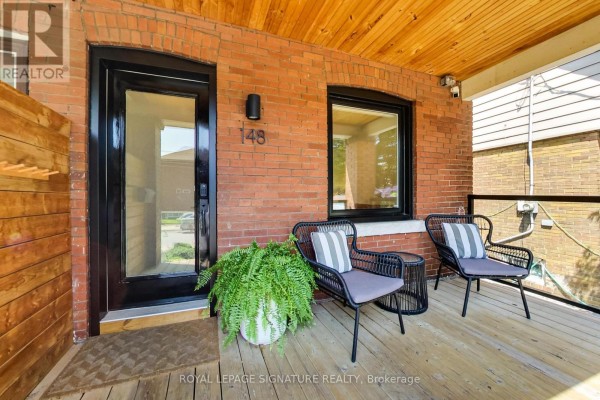 Covered porch with two chairs, a table, and a large potted fern. - 148 Mortimer Avenue, Toronto