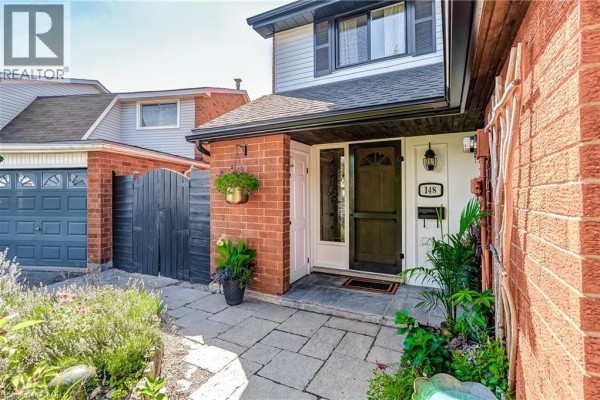 Front entrance of a townhouse with a brick facade, paved walkway, and white door with glass. - 148 St Andrews Drive, Hamilton