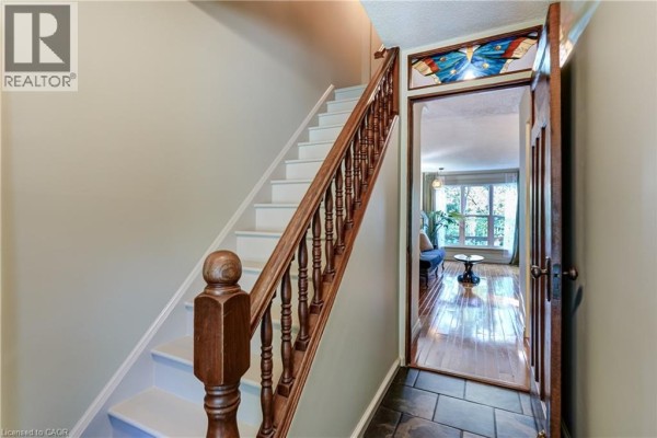Interior entryway with a wooden staircase, stone flooring, and a view of the living room. - 148 St Andrews Drive, Hamilton