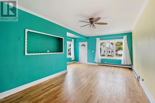 Living room with teal and yellow walls, hardwood floors, and a ceiling fan. - 148 Walnut St, Sault Ste  Marie