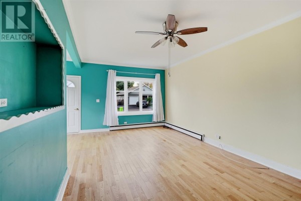 Living room with teal and yellow walls, hardwood floors, a ceiling fan, and windows. - 148 Walnut St, Sault Ste  Marie