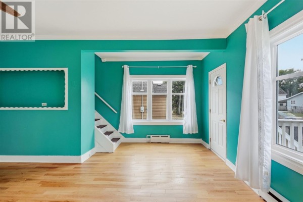 Interior view of a living room with teal walls, hardwood floors, and stairs to the side. - 148 Walnut St, Sault Ste  Marie