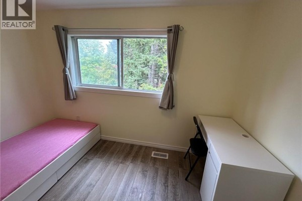 Bedroom with a twin bed, white desk, black chair, and a window overlooking trees. - 148 Weber Street N Unit# A, Waterloo