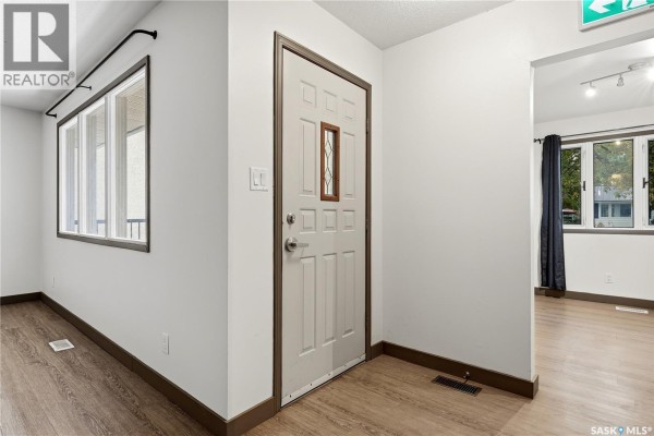 Interior entryway with white walls, beige door with a small window, and wood-look vinyl flooring. - 148 Woodward Avenue, Regina