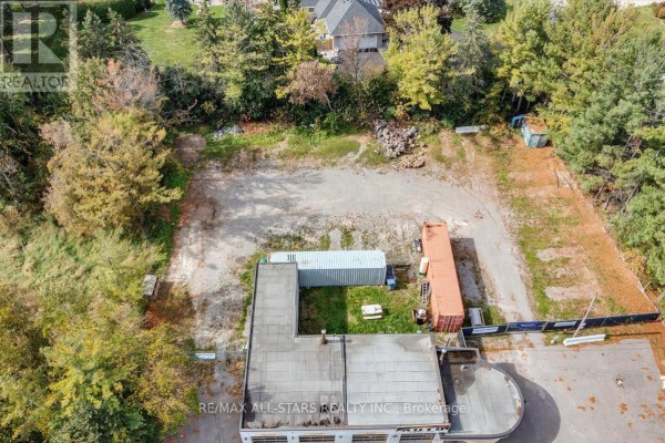 Aerial view of the rear of the commercial building, showing storage containers and undeveloped land. - 14806 Woodbine Avenue, Whitchurch Stouffville