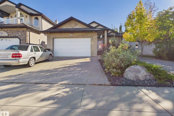 Street view of the house with a silver car parked on the gravel driveway. - 14815 16 St Nw, Edmonton