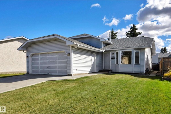 Front view of a light blue house with a garage door, bay window, and green lawn. - 14819 35 St Nw, Edmonton