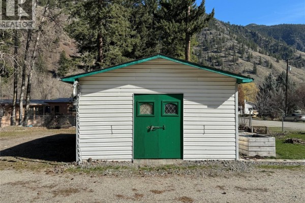White detached garage with a green double door and diamond-shaped windows. - 1483 Main Street, Olalla