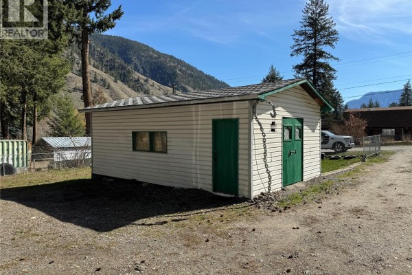 Side view of a white detached garage with a green door and window. - 1483 Main Street, Olalla