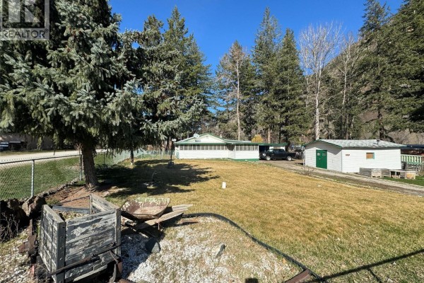 Exterior view of a white house and detached garage with a large grassy yard. - 1483 Main Street, Olalla