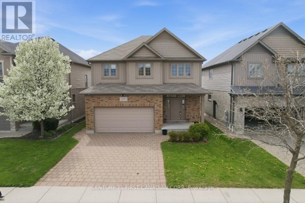 Front view of a two-story house with beige siding, brick lower level, and an attached garage. - 1485 Riverbend Road, London South