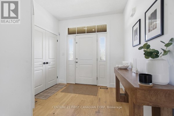 Interior foyer with white walls, hardwood floors, a console table, and double doors. - 1485 Riverbend Road, London South
