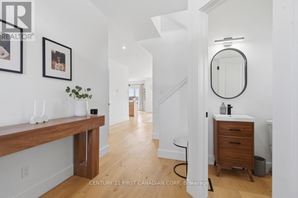 Interior foyer and hallway with white walls, hardwood floors, a console table, and a powder room. - 1485 Riverbend Road, London South