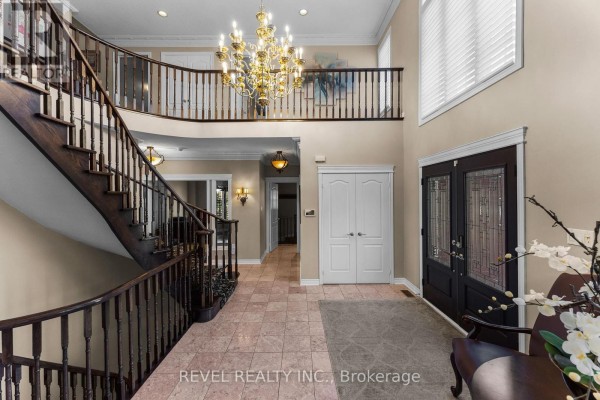 Spacious foyer with a grand wooden staircase, tiled floor, and chandelier. - 1486 Ashwood Gate, Pickering