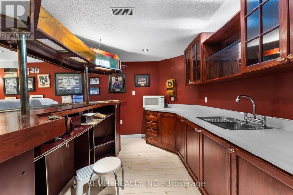 Basement wet bar with kitchenette, wooden bar, and sports photos - 1486 Ashwood Gate Pickering