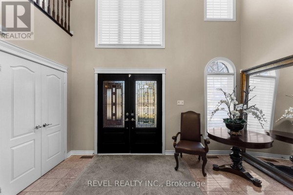 Interior foyer with double doors, tiled floors, a large mirror, and decorative table. - 1486 Ashwood Gate, Pickering