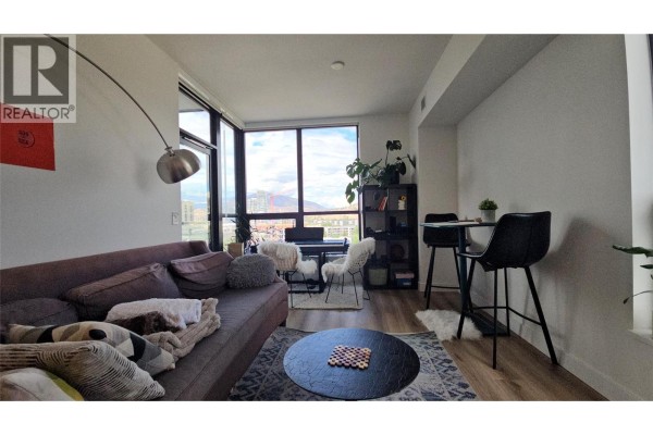 Living area with a couch, dining nook with bar stools, and floor-to-ceiling windows. - 1488 Bertram Street Unit# 1008, Kelowna