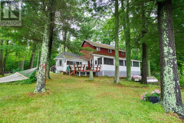Exterior of a red and white house with a wooden deck and screened-in porch. - 148b Oak Shores Lane, Frontenac