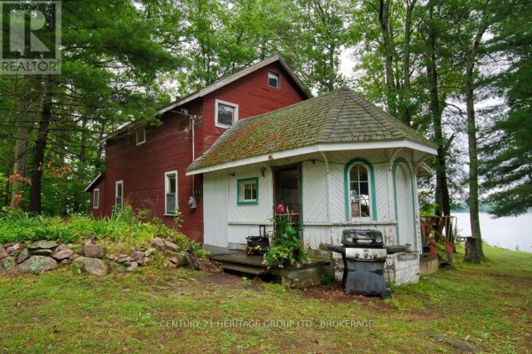 Side view of a red and white house with a bay window and a propane grill on the porch. - 148b Oak Shores Lane, Frontenac