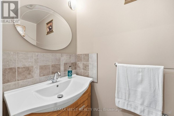 Bathroom vanity with oval mirror and white towel - 149 Deerglen Terrace Aurora