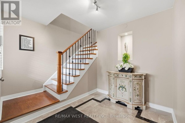Interior foyer with a decorative cabinet, staircase, and marble tile flooring. - 149 Deerglen Terrace, Aurora