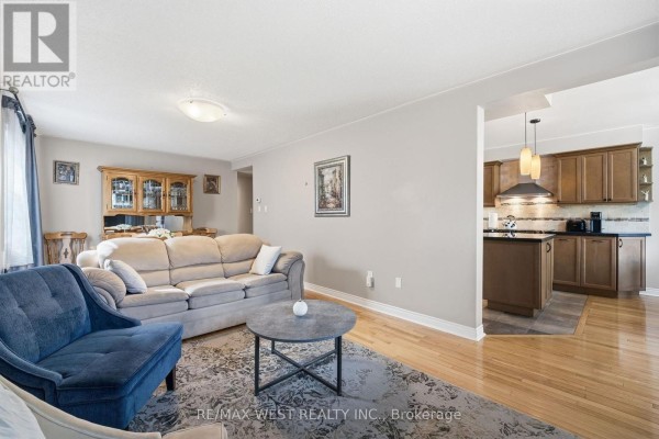 Living room with sofa and armchair opening to kitchen - 149 Deerglen Terrace Aurora