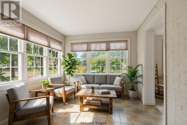 Sunroom with tiled floor, large windows, and modern grey furniture. - 149 Dufferin Avenue, Belleville