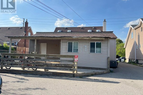 Rear exterior of a house with a covered wooden deck and beige siding. - 149 Finch Avenue W, Toronto