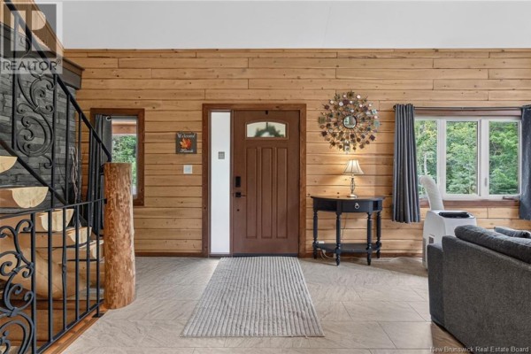 Entrance hall with wood-paneled walls, a wooden front door, and a stone fireplace. - 149 Maclean Crossroad Road, Irishtown