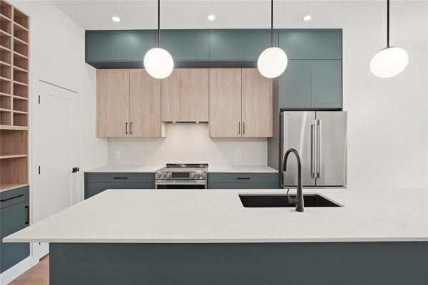 Modern kitchen with grey cabinets, wood uppers, and a large white island. - 149 Renfrew Street, Winnipeg