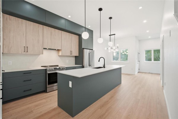Spacious kitchen with grey island, stainless steel appliances, and wood floors. - 149 Renfrew Street, Winnipeg