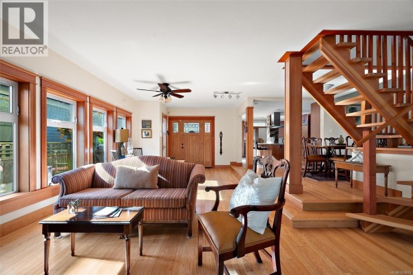 Living room with striped sofa, armchair, coffee table, and view of the entryway. - 149 St. Lawrence St, Victoria
