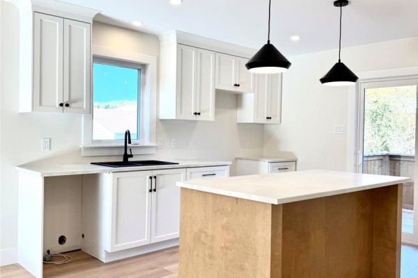 White kitchen cabinets with black hardware, a black sink, and a light-colored countertop island. - 1490 Thorburn Road, St  Philip’s