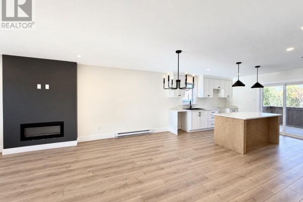 Open concept living space with a modern fireplace, light wood flooring, and a kitchen island. - 1490 Thorburn Road, St  Philip’s